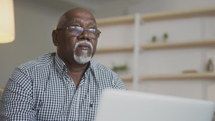 Online work for aged people. Close up portrait of senior african american man freelancer in eyeglasses typing on laptop - Powered by Adobe