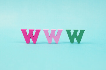 Multicolored wooden letters WWW on a pale blue background. Internet symbol World Wide Web. Creative...