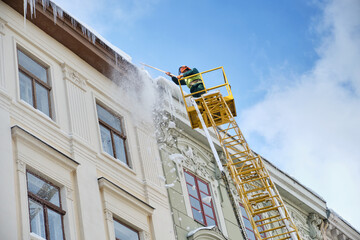 Public utilities on special vehicles remove icicles from the roofs of houses on the Rynok square in...