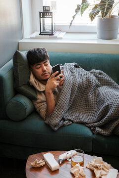Ill man on sofa using cell phone
