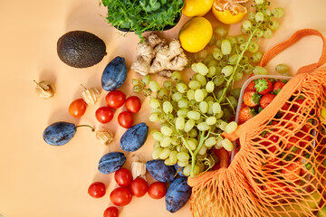 Flat lay Mesh grocery shopping eco friendly bag with fruits on orange canvas background, Zero waste cconcept, Local farmers market, shopping mall, top view, copy space, Plastic free items.