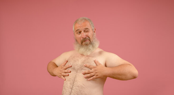 naked torso of a man with a gray beard, winks and covers the nipple with his hands on a pink background