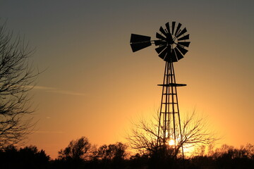 windmill at sunset with a colorful sky north of Hutchinson Kansas USA out in the country.