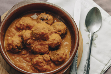 Meatball stew with tomato sauce in earthenware casserole dish.