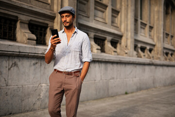 Young stylish man using the phone outdoors. Fashion happy man enjoy outdoors.