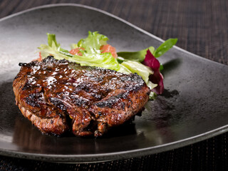 roasted filet mignon served with salad mic on a plate dark background