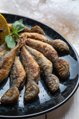 Plate of fried fresh fish red mullets serving with seasonal herbs, lemon