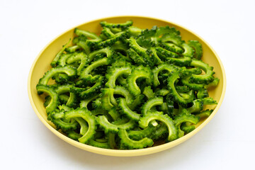Sliced bitter gourd in yellow plate on white background.