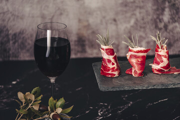 Plate of delicious Iberian ham on a wooden table background. Appetizing slices Iberian ham. Acorn-fed Iberico Ham. Pata negra, spectacular vision of sliced ham. Typical spanish food.