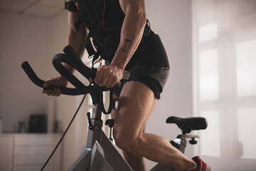 Obraz na płótnie Canvas a young athlete riding a bike with an electrostimulation vest in a beauty clinic.