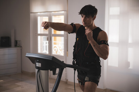 a young athlete hitting a punch with an electrostimulation vest in a beauty clinic.