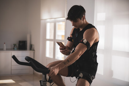 a young athlete riding a bike with an electrostimulation vest in a beauty clinic.