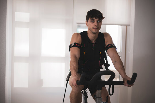 a young athlete riding a bike with an electrostimulation vest in a beauty clinic.