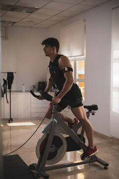 a young athlete riding a bike with an electrostimulation vest in a beauty clinic.