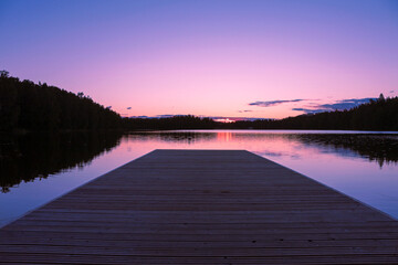 Colorful sunset on a lake in Finland. Perspective of the wooden pier