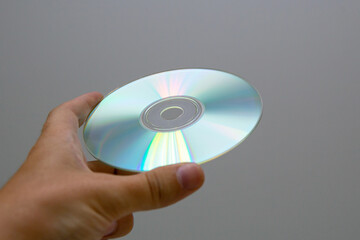 A hand holds a dvd disc in a close-up.