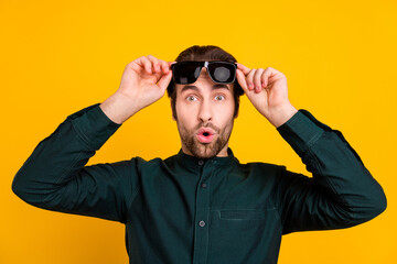 Photo of shocked impressed young man wear smart casual outfit arms dark glasses isolated yellow color background