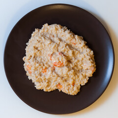Risotto with shrimp in cream sauce on a dark plate
