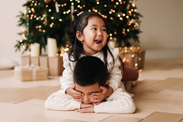 Funny happy mixed Asian kids brother and sister hugging giving gift boxes celebrating Christmas...