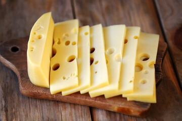 Sliced maasdam cheese on a wooden surface.