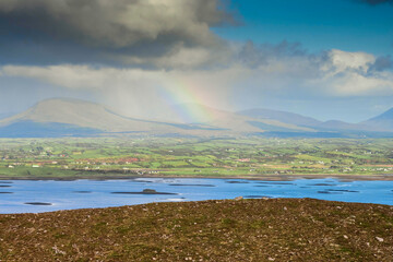 Atlantic ocean with many small islands and dramatic clouds and colorful rainbow. View from Croagh Patrick on amazing nature scenery. County Mayo, Ireland. Irish landscape scene