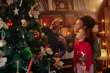 Mom, dad and little daughter decorating christmas tree