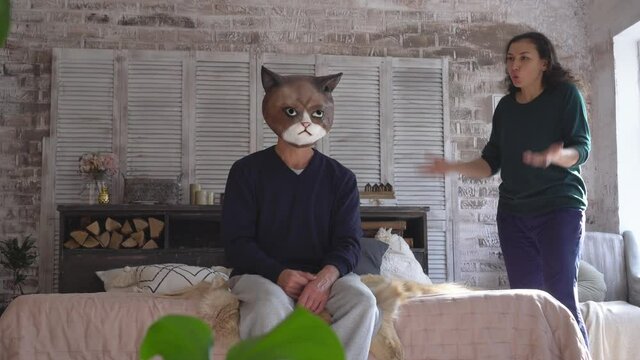 Sad depressive lazy passive man in a cat mask. A married couple quarrels. The wife scolds her husband. Stressed cat looking frustrated thinking of money debt, budget loss, unemployment, bankruptcy