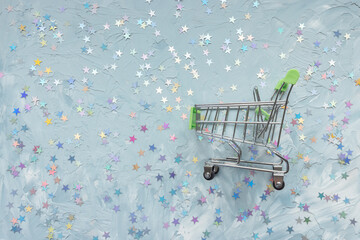 Shopping cart and on blue with stars festive background. Winter holidays, Christmas and gift...