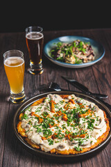 Two glass of beer and autumn or fall food over black background on rustic wooden table.