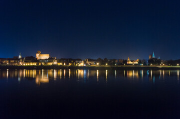Fototapeta na wymiar Night view of panoramic view on Old town of Torun city walls and reflection in Vistula river.