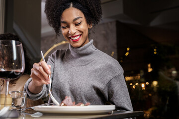 Beauty cheerful young Afro American woman eating at restaurant - one African descent girl dining indoor.