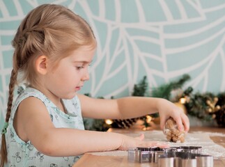 Little girl making Christmas cookies. Child cutting ginger cookies out of dough. Christmas holidays, moments
