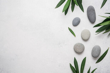 Obraz na płótnie Canvas Spa stone light gray background with green plant leaves and zen pebble stone. Top view, copy space
