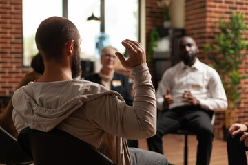 Man with addiction sharing mental health issues with group at aa meeting, talking to therapist. People having conversation about depression and rehabilitation at therapy session. - obrazy, fototapety, plakaty
