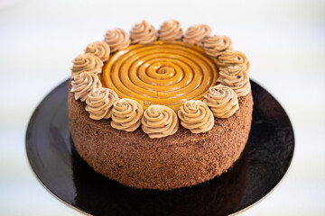  Delicious chocolate and caramel cake on black plate, white background.