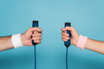 cropped view of man and woman holding skipping rope on blue