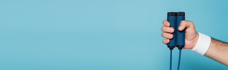 cropped view of sportsman holding skipping rope on blue, banner © LIGHTFIELD STUDIOS
