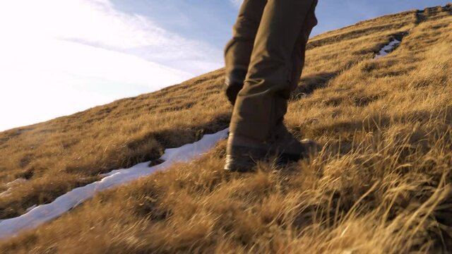 Hiker's feet walking in the mountain summit. Man walking on the mountain ridge. Feet in Hiking Boots Walking through the Mountain in fall. Walking through woodland. Low angle view of a hunter.