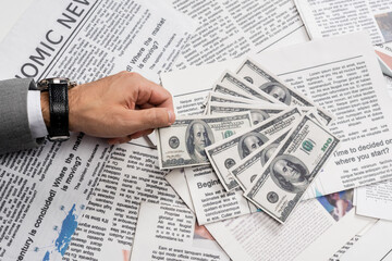 Fototapeta premium KYIV, UKRAINE - NOVEMBER 1, 2021: cropped view of man holding dollar banknote near printed newspapers