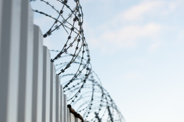 Close-up of a barbed wire fence against a clear blue sky. The concept of striving for freedom.