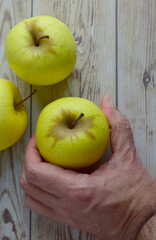 Picking a yellow apple on a rustic wooden table. Top view and copy space, vertical shot.