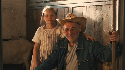 Obraz na płótnie Canvas Grandfather and granddaughter in barn