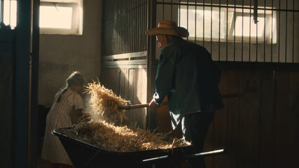 Grandfather and granddaughter giving hay to goats