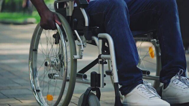 Man with disability using manual wheelchair outdoors, reduced mobility