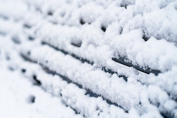 Fresh snow covering bench back closeup. Frozen wood planks after snowfall. Abstract winter background. Selective focus.