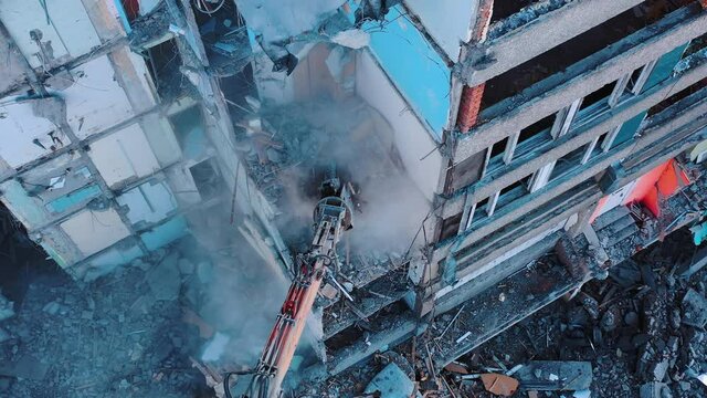 Process of dismantling a structure after an earthquake. Destruction of walls and concrete blocks that were broken by the earthquake. Excavator dismantling high buildings.