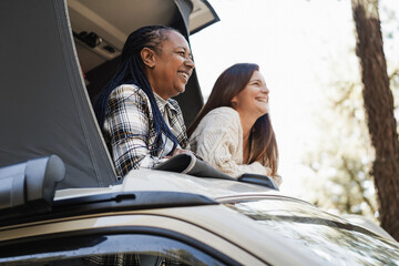 Senior women friends having fun inside camper van - Focus on african woman face