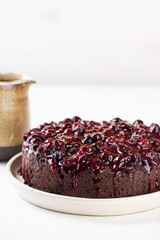 Eggplant chocolate cake with black currants on a white table. Sugar, gluten, lactose free, vegan.