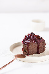 Piece of vegan chocolate brownie eggplant with black currants on a white table. Sugar, gluten, lactose free.