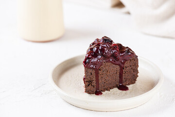 Chocolate brownie with cherries on a white plate. Sugar, gluten, lactose free, vegan.